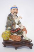 Oriental figure seated beside a water pot decorated with polychrome designs to the cloak and pot,