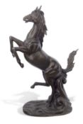 A contemporary bronzed metal model of a rearing horse set on a naturalistic base, 180cm high