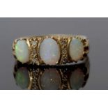 Three stone opal and diamond ring featuring three graduated oval shaped opals, highlighted between