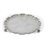 George V silver salver of plain shaped circular form having 'Chippendale' edge and raised on three