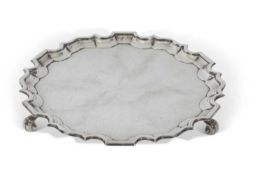 George V silver salver of plain shaped circular form having 'Chippendale' edge and raised on three