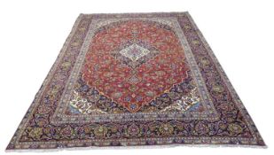 Iranian wool floor rug decorated with a large central red and blue panel with stylised floral detail