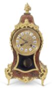 A boule mantel clock of shaped form, the case fitted with floral finial, the body applied with