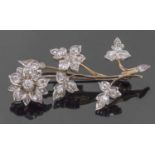 Precious metal diamond set floral spray brooch, the flowerhead and leaves decorated throughout