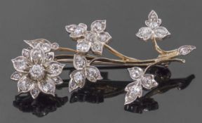 Precious metal diamond set floral spray brooch, the flowerhead and leaves decorated throughout