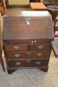 SMALL 18TH CENTURY OAK BUREAU WITH STEPPED AND WELL INTERIOR OVER A FOUR DRAWER BASE WITH BRACKET