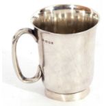 George V silver mug of flaring cylindrical form, plain polished design, C-scroll handle on a plain