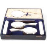Cased George V silver backed dressing table set comprising hand mirror, two hair brushes, two