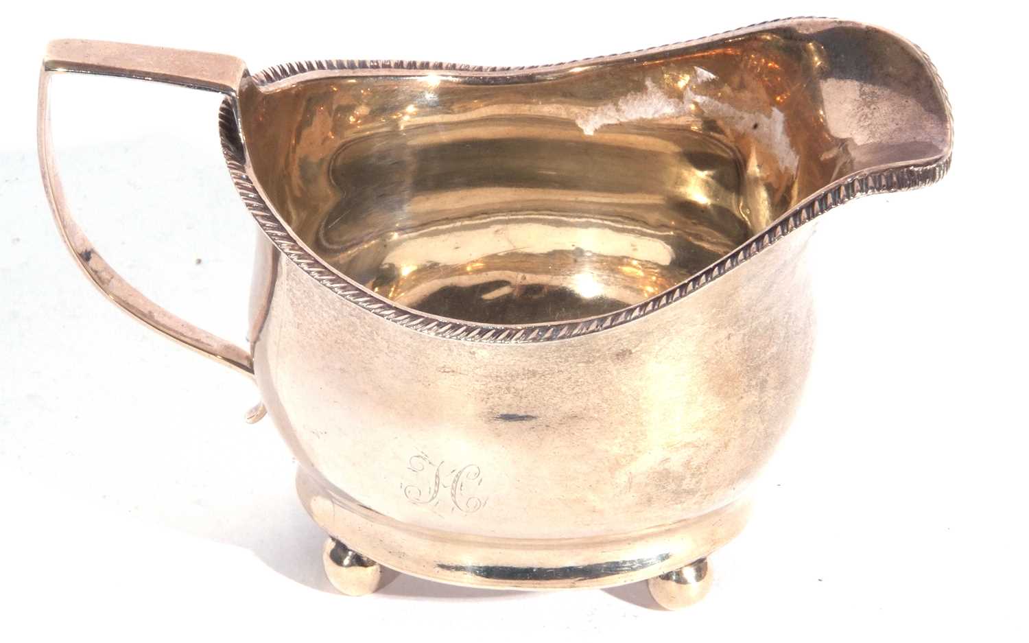 George III silver cream jug of plain form with gadrooned rim, angular looped handle, initialled