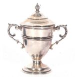 George V silver small trophy cup and lid with reeded mid-section and border, twin scroll capped leaf