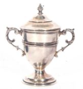 George V silver small trophy cup and lid with reeded mid-section and border, twin scroll capped leaf