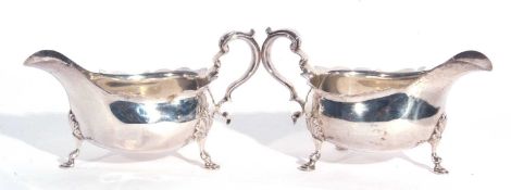 Large pair of George V silver sauce boats, each having card cut rims, capped scroll handles and