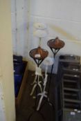 THREE METAL FLOOR STANDING CANDLE STANDS AND TWO METAL FRAMED FLOOR STANDING OIL LAMPS