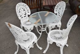 Set of four matching cast chairs with a small metal and glass bistro table