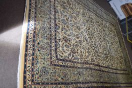 Large Meshed wool floor rug decorated with stylised floral detail on a pale background surrounded by