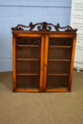 Small 19th century mahogany two-door bookcase cabinet with floral pediment over two glazed doors