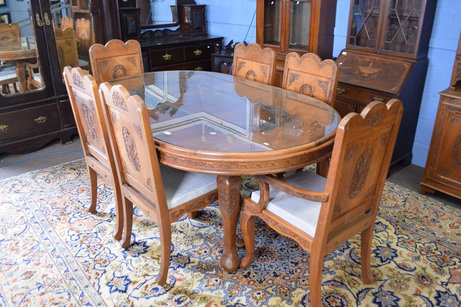 Kashmiri hardwood and floral carved dining room suite comprising an oval table with inset glass