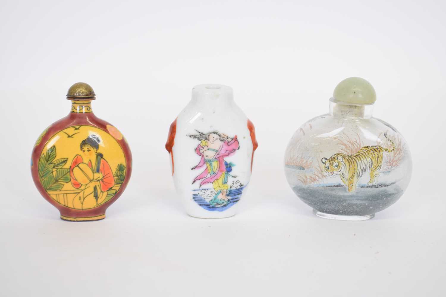 Small bag containing three Chinese scent bottles including a porcelain example with polychrome