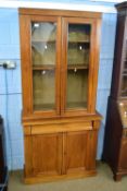 Small late Victorian pale mahogany bookcase cabinet with glazed top section over a base with