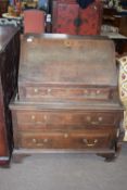 A composite oak fall front bureau with single drawer and fitted interior raised on a two-drawer