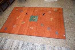 MODERN FLOOR RUG DECORATED WITH STYLISED ANIMALS AND PLANTS ETC ON AN ORANGE BACKGROUND, 187CM WIDE