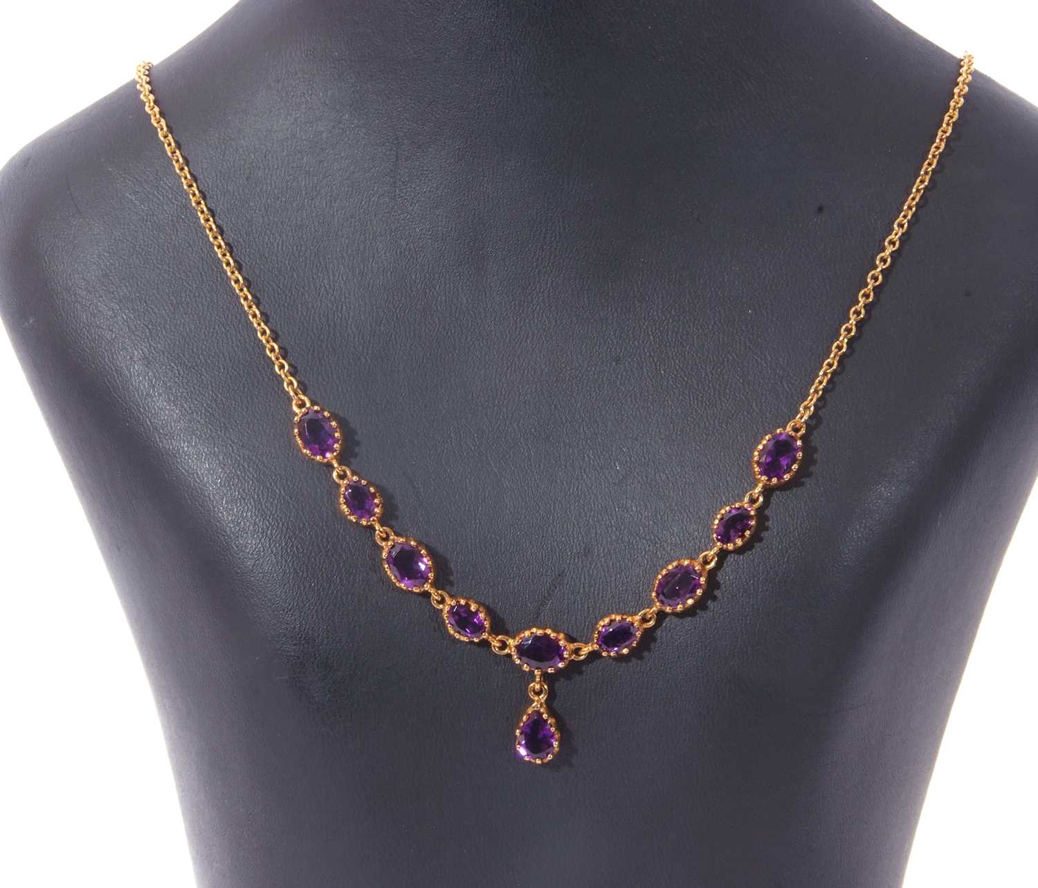 Modern amethyst necklace, a design featuring nine graduated oval cut amethysts in multi-claw cut