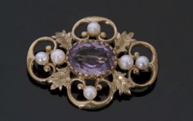 9ct gold amethyst and seed pearl open work scroll and leaf brooch centring an oval faceted amethyst,