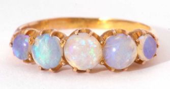 Five stone opal ring, line set with graduated round cabochon cut opals, set in a mid-grade yellow