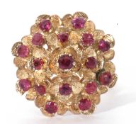 Modern ruby cluster ring, a dome design of floral engraved petals set with 17 small rubies in a