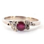 Precious metal, ruby and diamond ring centring a small round faceted ruby raised above small mixed