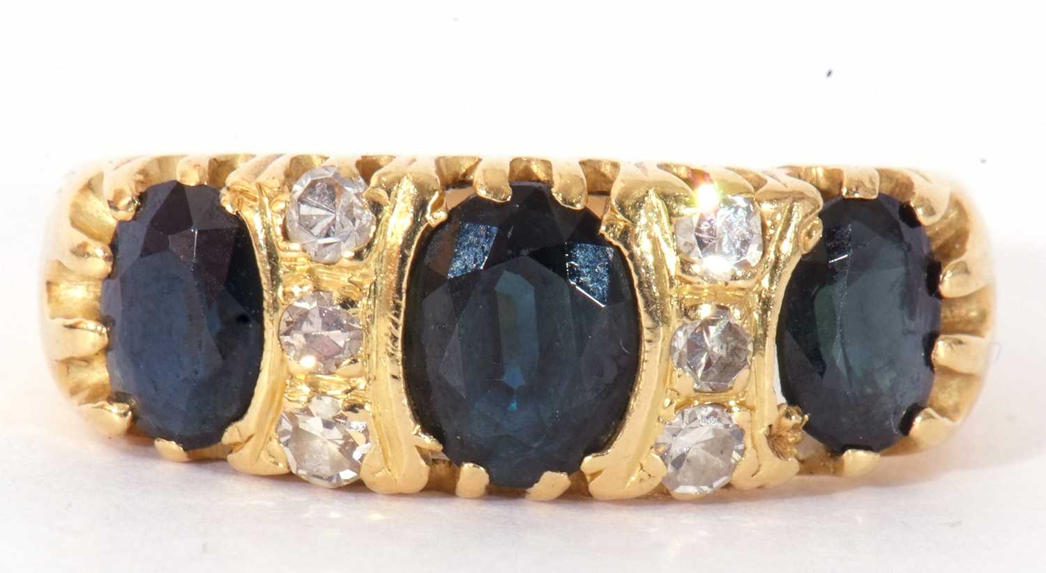 Sapphire and diamond ring featuring three graduated oval faceted sapphires highlighted between