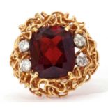 Modern garnet and diamond ring, the central cushion shaped garnet 14 x 10mm, highlighted with four