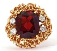 Modern garnet and diamond ring, the central cushion shaped garnet 14 x 10mm, highlighted with four