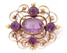 Yellow metal and amethyst brooch, the ornate scroll and bead openwork frame decorated with five