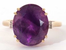 Modern 18ct gold, amethyst and diamond ring, the oval faceted amethyst four claw set and raised in a