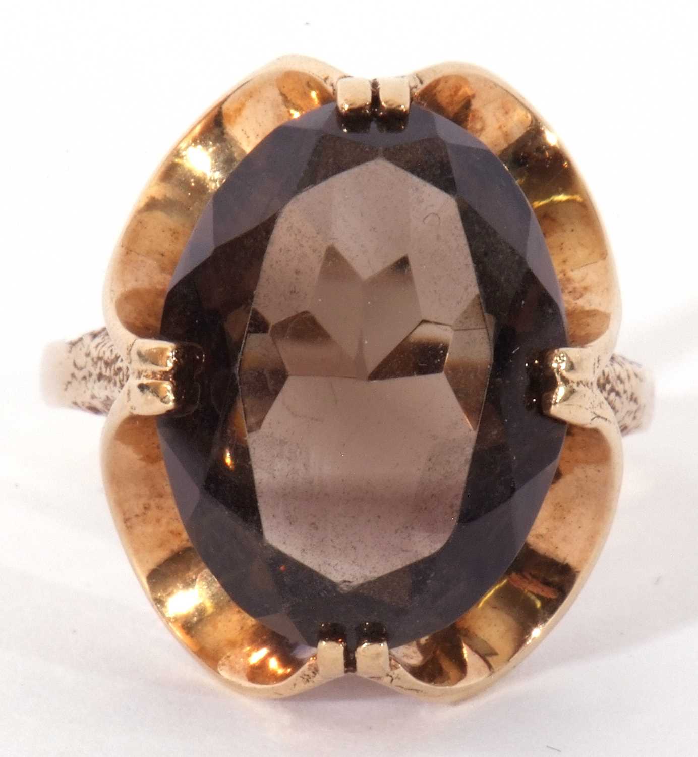 9ct gold smoky quartz dress ring, the large oval faceted quartz cardinal set in a stylised mount,