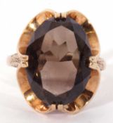 9ct gold smoky quartz dress ring, the large oval faceted quartz cardinal set in a stylised mount,