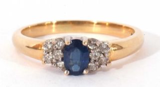 Sapphire and diamond ring centring an oval faceted sapphire, 6mm x 4mm, flanked by small diamond set