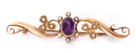 Amethyst and seed pearl scroll brooch centring an oval faceted amethyst in millegrain edge setting