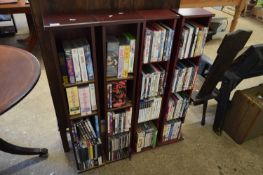 FOUR SMALL SHELF UNITS CONTAINING RANGE OF VARIOUS DVDS, VIDEOS AND CDS