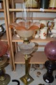 OIL LAMP WITH BRASS COLUMN BASE, CLEAR GLASS FONT AND A FRILLED TINTED SHADE