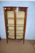 Edwardian mahogany bow front two door display cabinet with shelved interior, raised on tapering