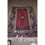 20th century Middle Eastern wool floor rug decorated with a large central red lozenge with