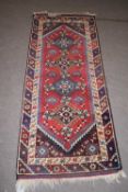 20th century Middle Eastern wool floor rug decorated with a central red lozenge, 186 x 74cm