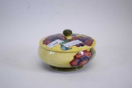 A Moorcroft mid-20th century circular box and cover with tube lined floral decoration on a yellow