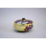 A Moorcroft mid-20th century circular box and cover with tube lined floral decoration on a yellow