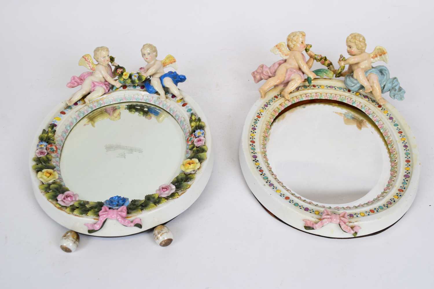 Oval Continental porcelain mirror, probably Sitzendorf, the mirror surmounted with two cherubs, 28cm