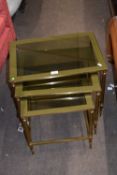 Nest of three 20th century brass finish and smoked glass top occasional tables, largest 52cm wide