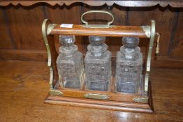 Late 19th or early 20th century oak and brass mounted tantalus containing three square cut glass