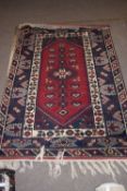 20th century Middle Eastern wool floor rug decorated with a large central red lozenge with
